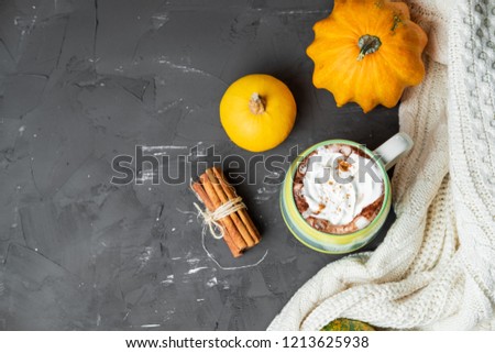 Spicy pumpkin latte with cinnamon and autumn leaves on a gray background