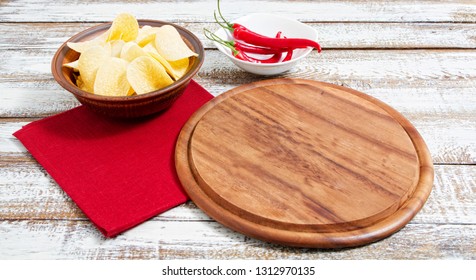 Spicy Red Chilli Potato Chips And Empty Board On A Wooden Table