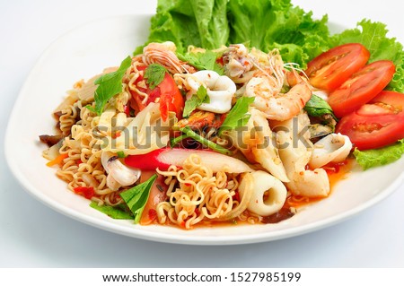 Spicy Seafood Instant Noodle Salad. Instant noodle spicy salad with shrimp, squid, Mussels, crab sticks, fresh vegetables, tomatoes, onions. Thai food style.