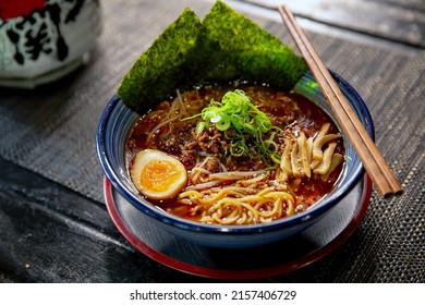 Spicy Sichuan Dandan noodles ramen with chopstick in the traditional Japanese ramen restaurant, with a ramen bowl and Japanese fonts sake barrel translation: Invincible Great Gate