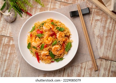 Spicy stir fried instant noodle with shrimps and thai basil leaves in white plate.Top view - Powered by Shutterstock