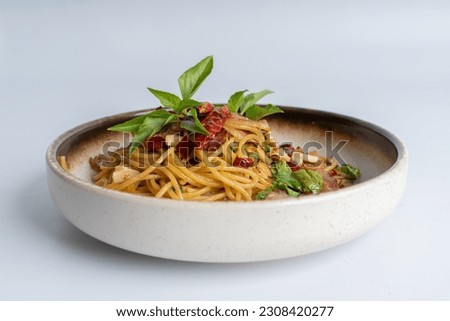 Spicy Thai basil pork pasta on white dish with white background. Italian food fusion Thai food. Tasty appetizing Italian fusion spicy spaghetti pasta with meat, chili, Thai basil. Italian fusion food.