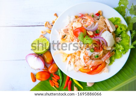 Spicy Vermicelli Seafood Salad with vegetable ingredient on wood white background, Thai food Street food Concept.Top View