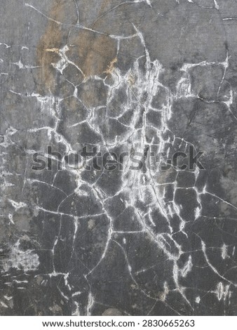 Spiderweb crazing crack pattern on dark gray plaster cement background