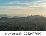 Spikey silhouette hills with misty and hazy clouds with yellow sunset blue sky background in sonora desert heat. In the suburbs near Tuscon Arizona in North American southwestern United States.