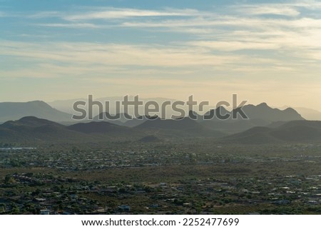 Spikey silhouette hills with misty and hazy clouds with yellow sunset blue sky background in sonora desert heat. In the suburbs near Tuscon Arizona in North American southwestern United States.