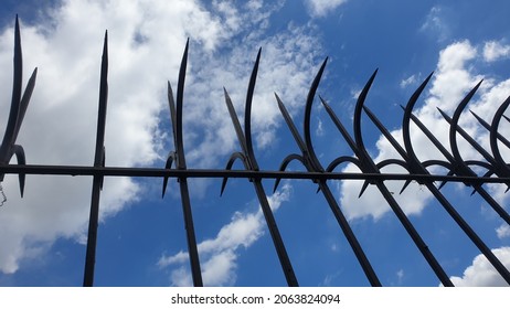 Spiky iron fences prevent people from climbing over, Anti-climb spikes with clouds and sky