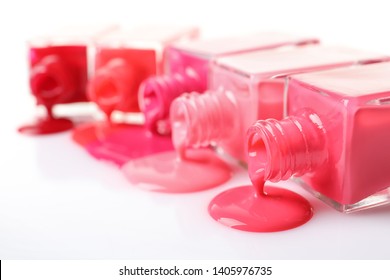 Spilled different nail polishes and bottles white background  closeup