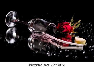 Spilled Drink With Roses And A Straw, Garnish On A Reflective Surface Isolated On A Black Background