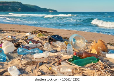 Spilled garbage on the beach of the big city. Empty used dirty plastic bottles. Dirty sea sandy shore the Black Sea. Environmental pollution. Ecological problem. Moving waves in the background