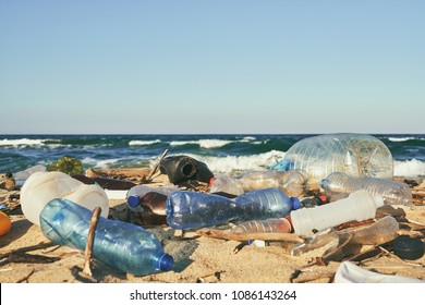 Spilled garbage on the beach of the big city. Empty used dirty plastic bottles. Dirty sea sandy shore the Black Sea. Environmental pollution. Ecological problem. Moving waves in the background - Powered by Shutterstock