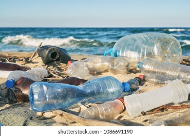 Spilled garbage on the beach of the big city. Empty used dirty plastic bottles. Dirty sea sandy shore the Black Sea. Environmental pollution. Ecological problem. Bokeh moving waves in the background 