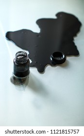 Spilled Ink Is On A Glass Table With Bottle Of Ink And Pen Ink.