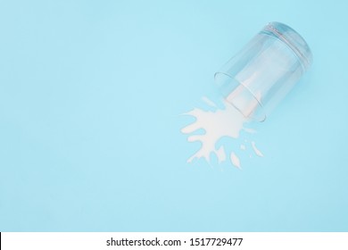 Spilled milk. Overturned glass with milk on blue background. Dairy abandonment concept Copy space Top view. - Powered by Shutterstock