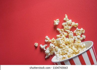 Spilled popcorn on a red background, cinema, movies and entertainment concept - Shutterstock ID 1104743063
