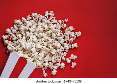 Spilled popcorn on a red background. Snack. Film premiere. Rating of the best movies. Watch a movie. The atmosphere of the cinema. Movie night.