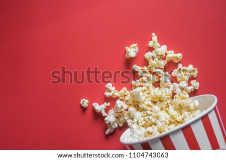 Spilled popcorn on a red background, cinema, movies and entertainment concept