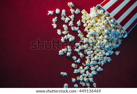 Spilled popcorn on a red background, cinema, movies and entertainment concept