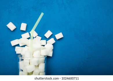 Spilled Sugar From A Glass On A Blue Background. Giant Sugar Concentration In Everyday Beverages.