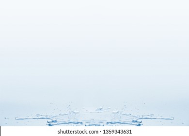 Spilled water on a table with splashes and drops on a white blue background.