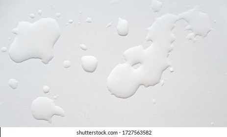 Spilled water on a white textured surface. Background. Top view.