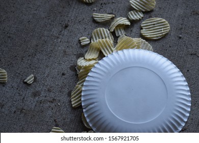 Spilled White Paper Plate Of Ruffled Potato Chips.