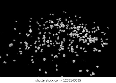 Spilled white sea salt on a black background. 	
clear crystalline pebbles on a black background