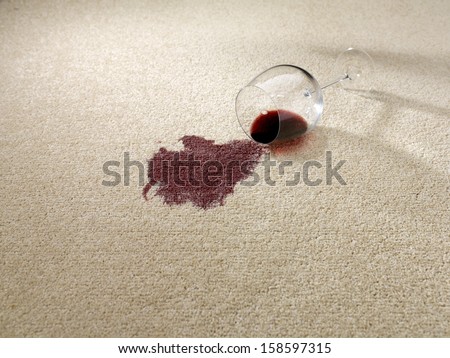 Spilt red wine from wine glass on carpet
