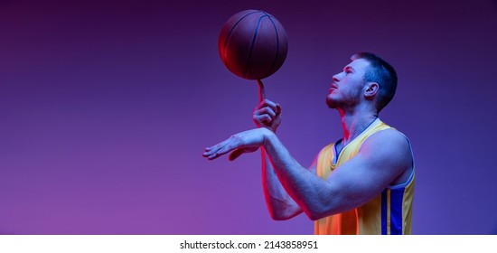 Spin. Studio shot of muscled man, basketball player training with ball isolated on purple background in neon light. Concept of sport, achievements, competition, hobby, active lifestyle. Flyer