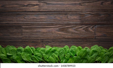 Spinach Background Of Fresh And Salty Spinach Leaves With Copy Space On A Wooden Table. Banner Overhead View