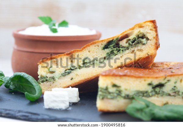 Spinach and cheese quiche tart\
served with yoghurt in clay bowl.  Spinach pie for healthy\
breakfast.