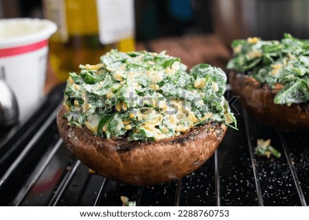 Spinach and Cheese Stuffed Mushrooms on a Sheet Pan: Closeup view of uncooked portobello mushroom caps stuffed with spinach and cheese on a wire rack