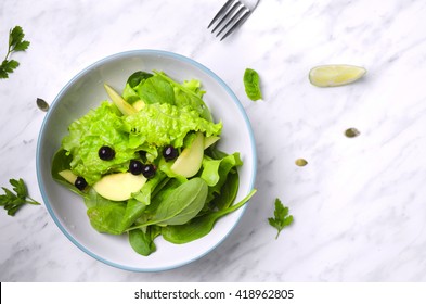 Spinach salad with fruit on marble with fork . Spinach salad with fruit on marble. Spinach veggies salad . Organic spinach salad. Green spinach salad. Spinach salad with ingredients