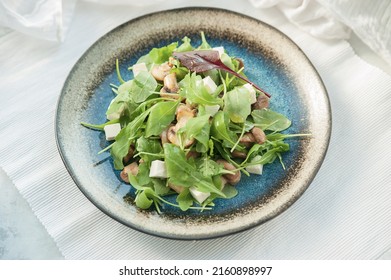 Spinach Salad With Mushrooms And Feta Cheese On A Blue Plate