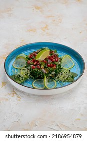 Spinach Salad With Pomegranate Berries On A Blue Plate
