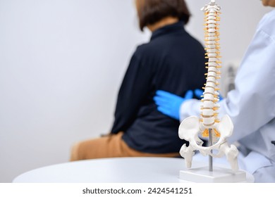 Spinal Focus Picture An orthopedic surgeon or therapist is showing a spinal model and explaining to a female patient her spinal problems. Health care concept and aging and back pain - Powered by Shutterstock