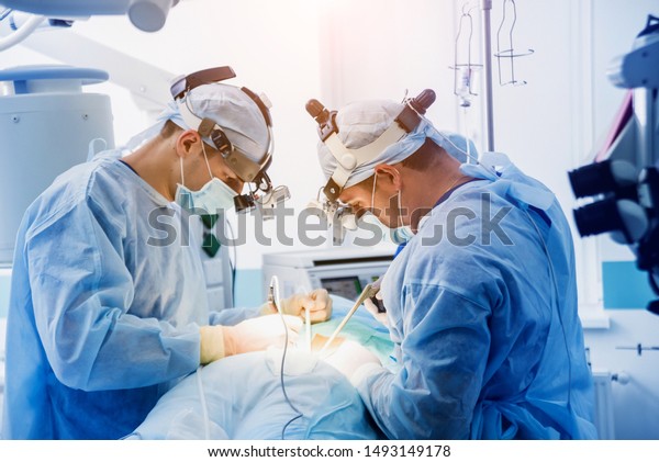Spinal\
surgery. Group of surgeons in operating room with surgery\
equipment. Laminectomy. Modern medical\
background