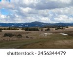 Spingtime photo of snow melting from the fields near southwick idaho with a mountain backdrop and a blue sky with white clouds