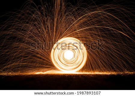 Spinning and burning Steel wool sparkle fire in the circle shape with long speed shutter shoot glowing light line to the ground.