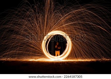 Spinning and burning Steel wool sparkle fire in the circle shape with long speed shutter shoot glowing light line to the ground.