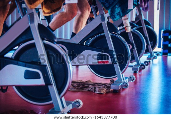 Spinning class, group activity on stationary\
bike. Team cardio excercise on\
bicycle.