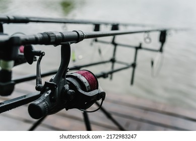 Spinning. Feeder fishing with reel. Rod pod. Fishing rods for pike, perch, carp on the pond. Angler with fishing technique. Fishing in rainy weather, rain. World Fisherman's Day, photo for article.