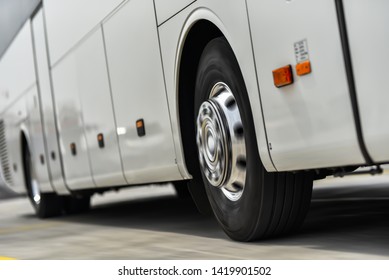 Spinning Wheels Of White Bus Liner Speeding By Road