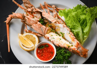 spiny lobster food on white plate, fresh lobster or rock lobster seafood with herb and spices lemon coriander parsley lettuce salad, lobster for cooking food and seafood sauce - top view