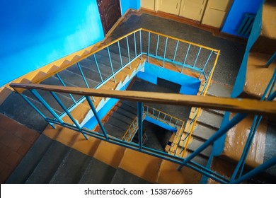 The spiral fire escape as orange staircase in squre style. A spiral staircase spiraling down about five floors. The winding concrete stairs are empty. The metal hand rail is nicely decorated.  - Powered by Shutterstock