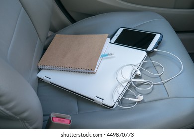 spiral notebook, notebook, smart phone, pencil, earphone on seat car