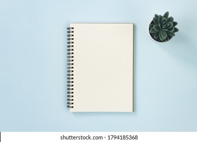 Spiral Notebook or Spring Notebook in Unlined Type and Office Plant on Blue Pastel Minimalist Background