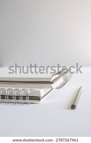 Spiral notebook stack and pencil arranged on white background in studio. Minimal stationery, elegant office style, modern branding, creative workspace, clean productivity.