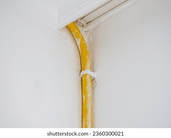Spiral pipe for the cable from a home refrigerator. Yellow pipe in the apartment. Elastic pipe. On the wall to the freezer. Home appliances