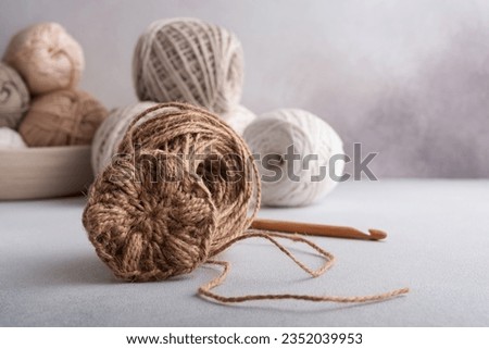 Spiral round jute napkin and wooden crochet hook on gray background. Concept for hobbies, needlework.